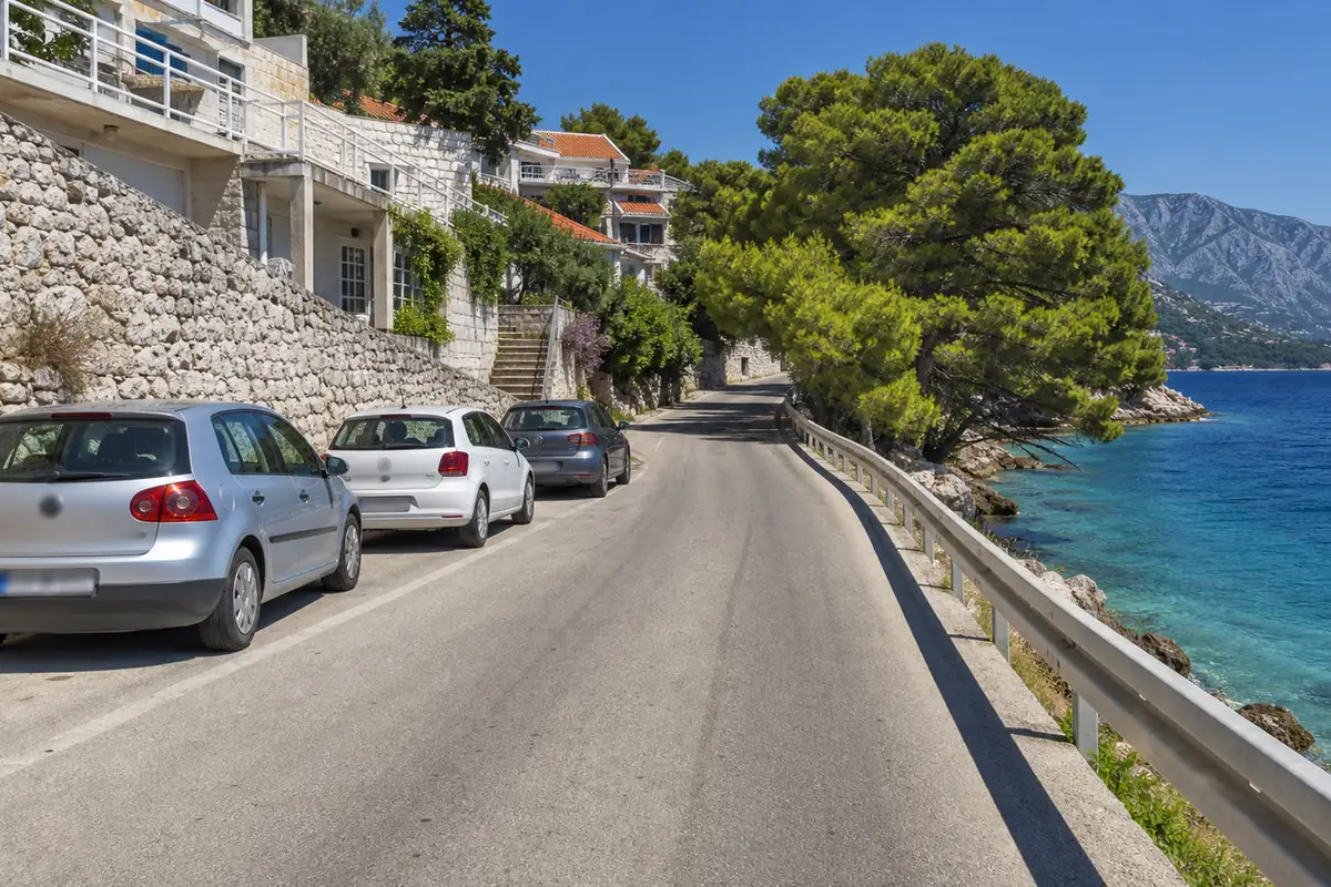 Schmale Küstenstraße zwischen Ferienhäusern und dem Meer in Dalmatien